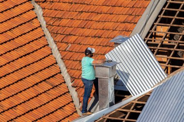 Marilia, Sao Paulo, Brezilya, 29 Temmuz 2022. Marilia 'nın merkezindeki ticari bir noktanın çatısını yenilemek için bir eve metal çarşaf döşeyen bir işçinin üst görüntüsü.