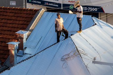 Marilia, Sao Paulo, Brezilya, 29 Temmuz 2022. Marilia 'nın merkezindeki ticari bir noktanın çatısını yenilemek için bir eve metal çarşaf döşeyen bir işçinin üst görüntüsü.