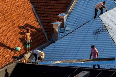 Marilia, Sao Paulo, Brezilya, 29 Temmuz 2022. Marilia 'nın merkezindeki ticari bir noktanın çatısını yenilemek için bir eve metal çarşaf döşeyen bir işçinin üst görüntüsü.