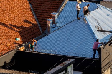 Marilia, Sao Paulo, Brezilya, 29 Temmuz 2022. Marilia 'nın merkezindeki ticari bir noktanın çatısını yenilemek için bir eve metal çarşaf döşeyen bir işçinin üst görüntüsü.