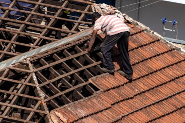 Marilia, Sao Paulo, Brezilya, 28 Temmuz 2022. Marilia şehir merkezindeki ticari bir noktanın çatısını yenilemek için bir evin fayanslarını söken bir işçinin üst görüntüsü