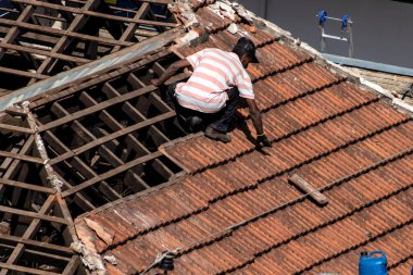 Marilia, Sao Paulo, Brezilya, 28 Temmuz 2022. Marilia şehir merkezindeki ticari bir noktanın çatısını yenilemek için bir evin fayanslarını söken bir işçinin üst görüntüsü