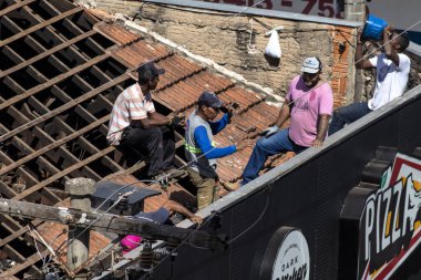 Marilia, Sao Paulo, Brezilya, 28 Temmuz 2022. Marilia şehir merkezindeki ticari bir noktanın çatısını yenilemek için bir evin fayanslarını söken bir işçinin üst görüntüsü