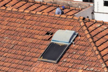 Marilia, Sao Paulo, Brezilya, 28 Temmuz 2022. Marilia şehir merkezindeki ticari bir noktanın çatısını yenilemek için bir evin fayanslarını söken bir işçinin üst görüntüsü