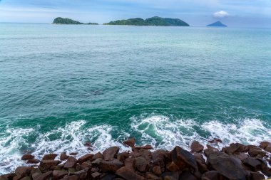 ocean waves beat against the rocks. We can see the foam on the sea. The rushed ocean, and ravishing warm water in Brazil