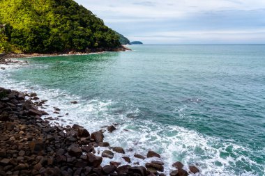 ocean waves beat against the rocks. We can see the foam on the sea. The rushed ocean, and ravishing warm water in Brazil