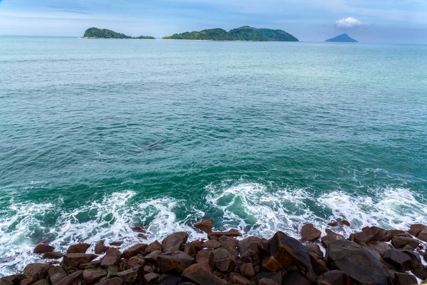 ocean waves beat against the rocks. We can see the foam on the sea. The rushed ocean, and ravishing warm water in Brazil