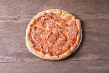 Ahşap bir masada jambon ve gorgonzola ile taze pişmiş pizzanın detayları.