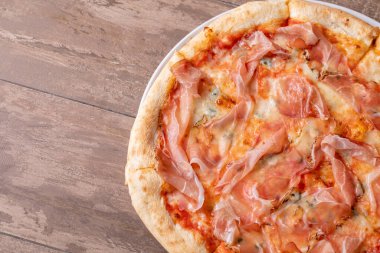 Ahşap bir masada jambon ve gorgonzola ile taze pişmiş pizzanın detayları.