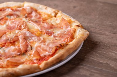 Ahşap bir masada jambon ve gorgonzola ile taze pişmiş pizzanın detayları.