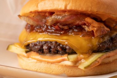 Tahta bir masanın üzerinde patates kızartması ve sosla sulu taze çizburgeri kapat.