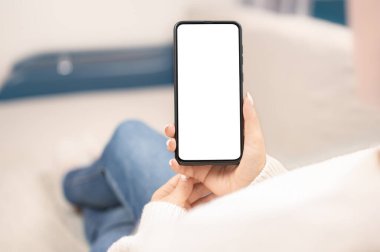 Akıllı cep telefonuyla evde çalışıyor. Evin içinde akıllı telefon çerçevesiz boş ekran kullanan bir kadın. Boş beyaz ekranlı cep telefonu kullanan kadın