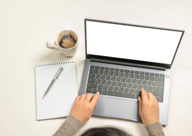 Boş ekranlı dizüstü bilgisayar, beyaz ekranlı eller ve aksesuarlar. İş kadını elleri beyaz ekranlı bir laptop kullanıyor. Çalışma alanı modeli. Boş ekranlı dizüstü bilgisayar. en üstteki görünüm