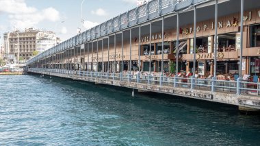 İSTANBUL, TURKEY - 12 Ekim 2021: Galata Köprüsü 'nden kafeleri ve restoranları olan İstanbul şehir manzarası. Galata Köprüsü boyunca yemek yiyen turistler