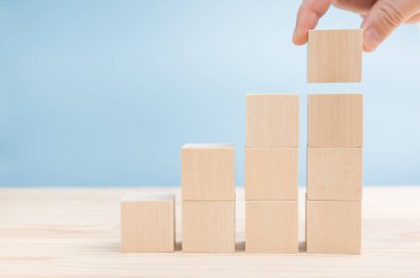 Boş tahta blokları düzenleyen adamların elleri ahşap masanın üzerinde üst merdiven şekli için diziliyorlar. Metnin için boş yer. İş kavramı büyüme başarı süreci