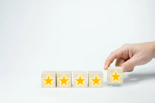 金の星印の木製のキューブ 男の手の白い背景に木製の5つ星の形を置く 最高の優れたサービス評価顧客体験のコンセプト 満足度 — ストック写真
