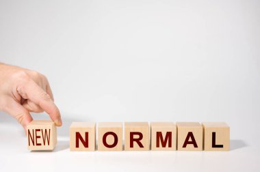 Yeni normal kelimeli ahşap küplerin el düzenlemesi. Yeni hayata ya da kilitlenme sonrası koronavirüs salgınına adapte olmak. Sosyal mesafeli kişisel hijyenle iş yapmak. Salgın hastalıktan sonraki yaşam