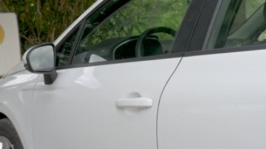 Kadın kapıyı açar ve beyaz bir arabaya biner.