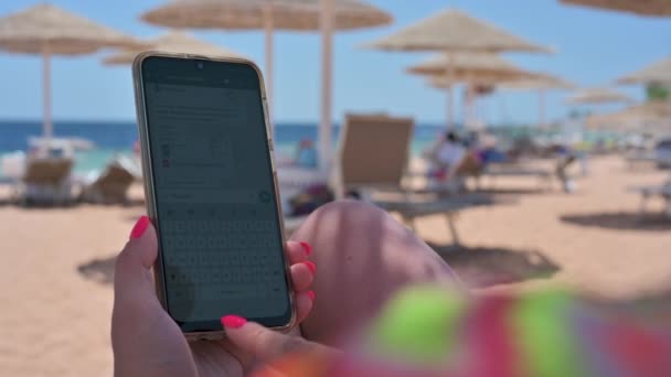 海滩上使用无法辨认的手机的女人 用信使输入消息 无法辨认的女人手里拿着手机 — 图库视频影像