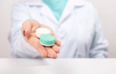 Doktor elinde tekrar kullanılabilir kontak lensleri olan bir kap tutuyor. Oftalmolog görme düzeltmesi için kontakt lens kullanmayı öneriyor. Oftalmoloji, mükemmel görüş ya da gözlükçülük
