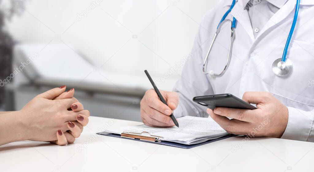 Doctors and patients sit and talk to the patient about medication. Unknown man doctor and female patient sitting and talking at medical examination in clinic. Doctor giving prescription to patient
