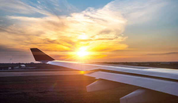 airplane wing at sunset. travel, air travel. Flying and traveling, view from airplane window on the wing on sunset time. Looking over aircraft wing in flight.