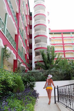 Şehrin arka planında atkısı olan sarı elbiseli bir kadın.