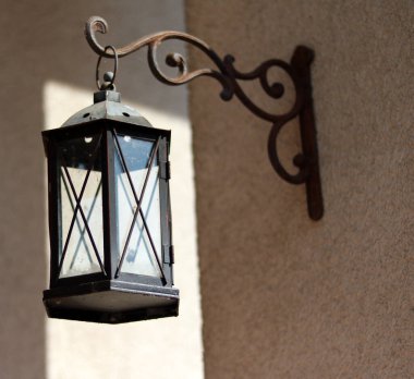 Duvarın arka planında eski model bir fener.