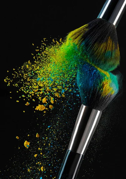 makeup brush with black eyeshadow and powder isolated on blue