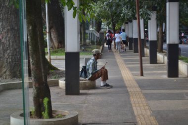 Bandung 20 Ağustos 2022 - Yaşlı adam sabah flüt çalarken patika kenarında oturuyor