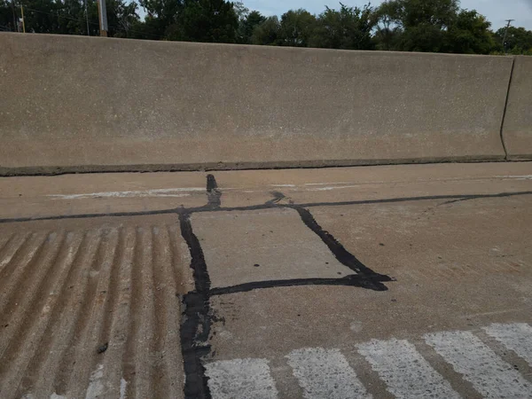 Concrete Barrier separating the different directions on the freeway with a plant growing in one of the cracks. Taken on M-59 in Utica, Michigan