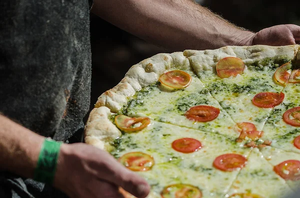 Uma Pessoa Segura Uma Pizza Com Molho Verde Coberto Com — Fotografia de Stock