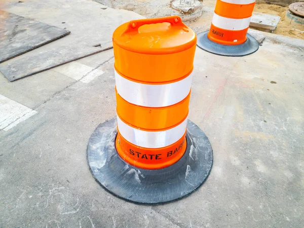 İnşaat alanındaki yolda yuvarlak turuncu bir trafik bariyeri..