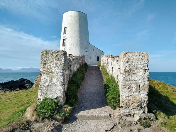Anglesey Adası 'ndaki Llanddwyn Yarımadası sahilindeki bir tepenin üzerindeki bir deniz fenerinin manzarası..