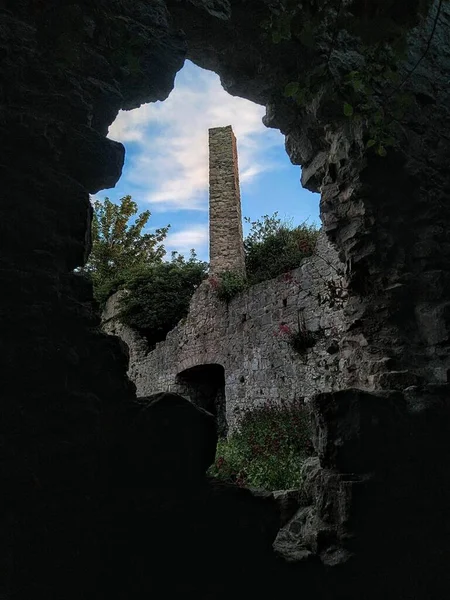 A view of a fireplace and chimney through some ruins on a hill in north Wales