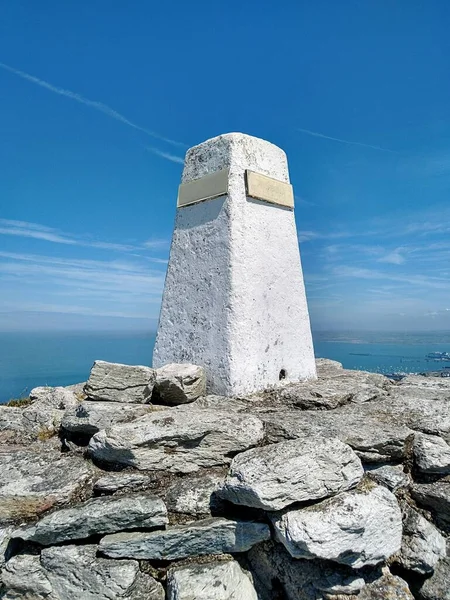 Galler 'in kuzey batı kıyısındaki Anglesey açıklarındaki Holyhead Dağı' nın zirvesindeki bir kayanın tepesindeki zirve / zirve işareti.