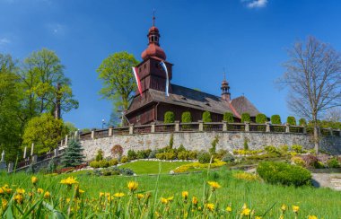 Polonya 'nın Lodygowice kentindeki ahşap kilisenin güzel manzarası. Ön planda karahindiba ile bir çiçek çayırı.