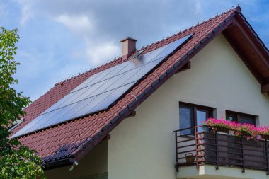 Tek bir ailenin kahverengi çatısındaki 6 kW fotovoltaik panel. Güneşten gelen ekolojik enerji. Hava güzel..