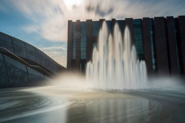 Polonya 'nın Katowice kentindeki NOSPR binasının (Polonya Ulusal Radyo Senfoni Orkestrası) önündeki çeşme. Uzun pozlama, bulanık su ve bulutlar.