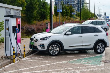 Elektrikli arabalar sokağın yakınındaki bir otoparkta bataryalarını şarj etmek için şarj istasyonuna bağlı. Elektrikli araçlar, geçiş.