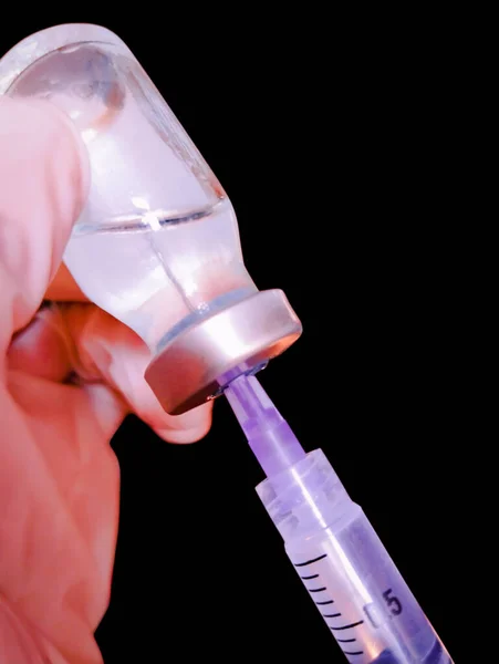 注射針とワクチンボトルでシリンジ手袋を手に保持バイアル医師看護師予防接種のための注射ショット充填ジャブを準備クローズアップビュー画像写真黒で隔離 — ストック写真