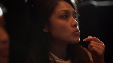 Asyalı bir kız sinemada oturur ve film izler.