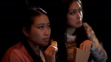 Sinemada film izleyen genç kadınlar.