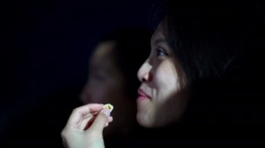 Sinemada film izleyen ve patlamış mısır yiyen genç kadınlar.