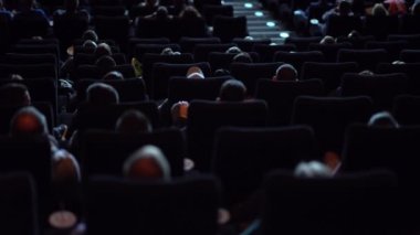 Sinema salonundaki izleyiciler büyük bir sinema izliyorlar.