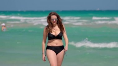 Rüzgarlı bir günde Miami Plajı 'nda bikini giyen genç ve güzel bir kadın.