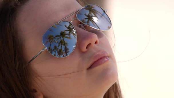 Close up skud af en kvinde iført solbriller på stranden under palmer – Stock-video