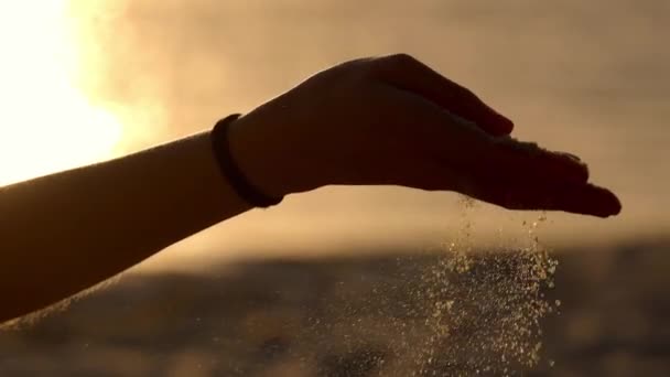 Ung kvinne som leker med sand på en strand ved solnedgang - sakte bevegelse – stockvideo