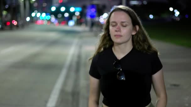 Ung kvinna förlorad i tankar vandrar längs gatan på natten — Stockvideo
