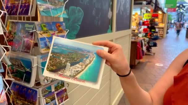 Letar efter Miami vykort på Bayside Marketplace Miami - MIAMI, FÖRENADE STATERNA - and RUARI 20, 2022 — Stockvideo